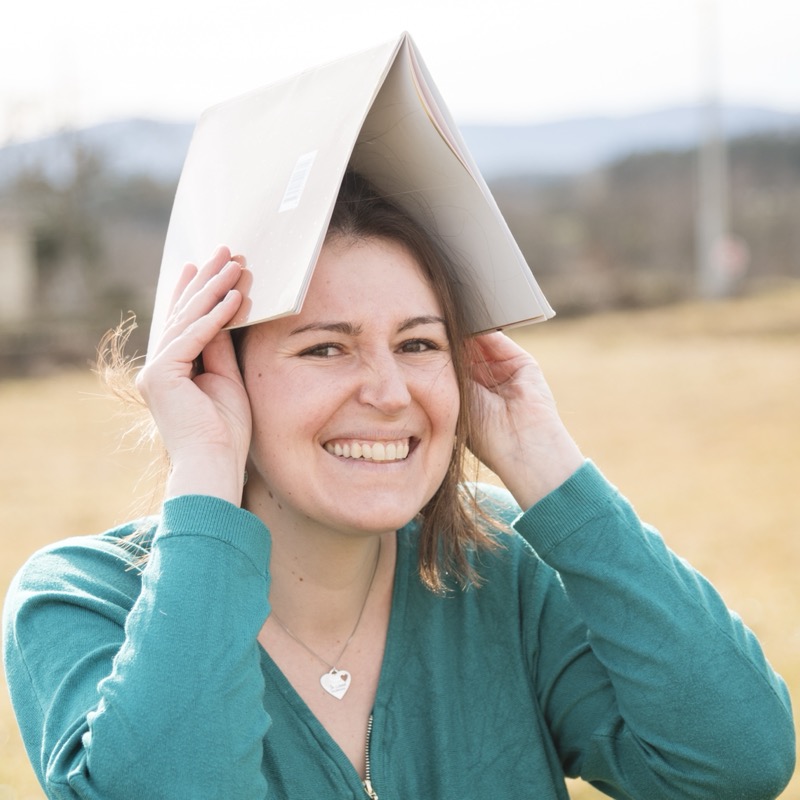 Tatiana sourit avec un livre ouvert posé sur la tête
